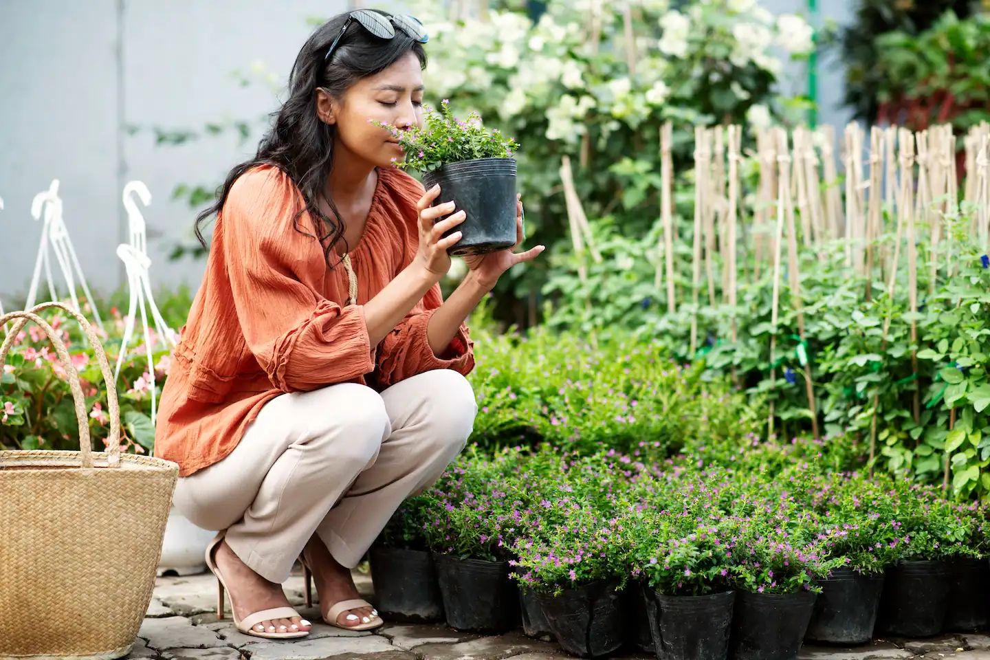 Woman in a garden centre holding a pot of plants.